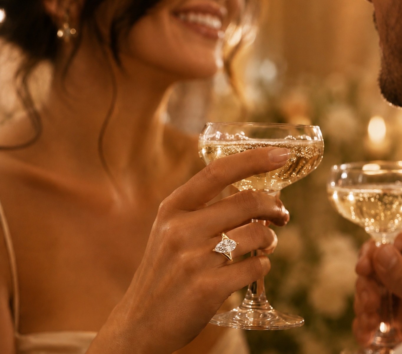 Woman raising a champagne coupe wearing a pear diamond ring