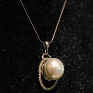 Pearl pendant with a pave diamond swirl on a fine chain