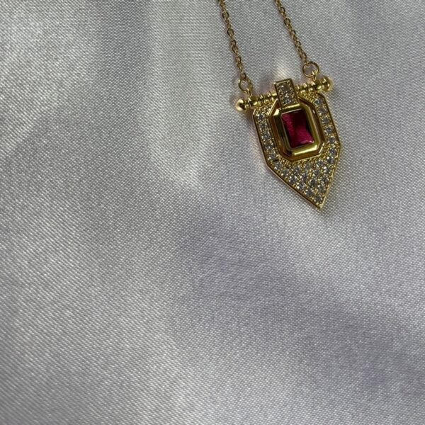 Ruby and diamond halo pendant on a yellow gold chain